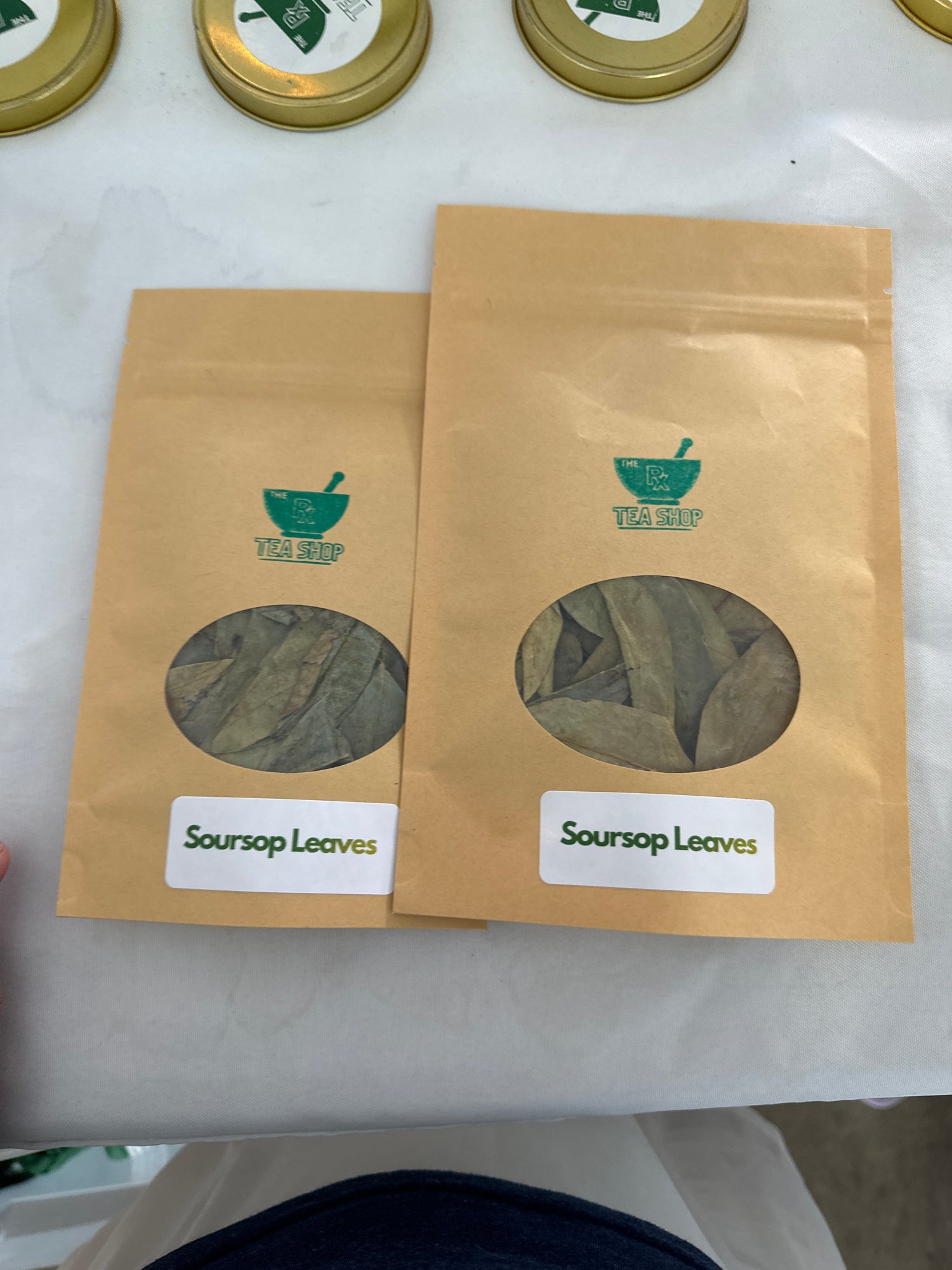 Image of two brown craft bags containing soursop leaves on a white tablecloth