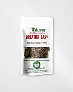 A white stand-up pouch of herbal tea blend from 'The Tea Shop' with a clear window showing the loose leaf tea inside. The packaging features green and red text, including the product name 'Breathe Easy'.