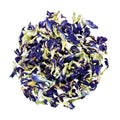 A pile of dried butterfly pea flowers, showing deep blue-purple petals mixed with pale green and yellowish-green stems, isolated on a solid white background.