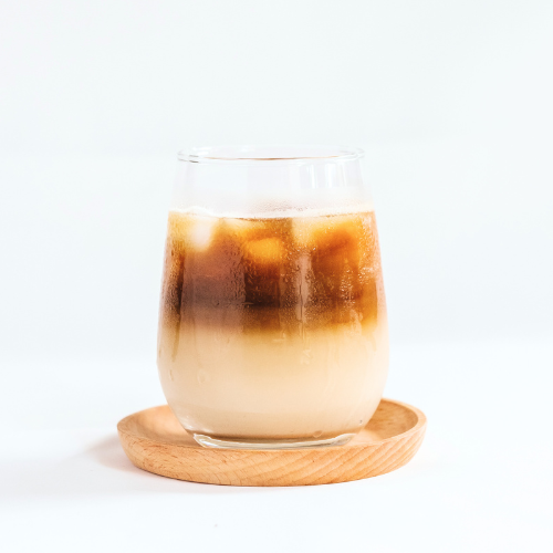 Chai Latte in clear glass on wooden coaster on white background