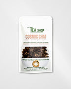 A stand-up pouch of 'The Tea Shop' Cosmic Chai herbal tea blend, featuring a white background with green and peach text and a clear window showing the dark herbal tea inside.