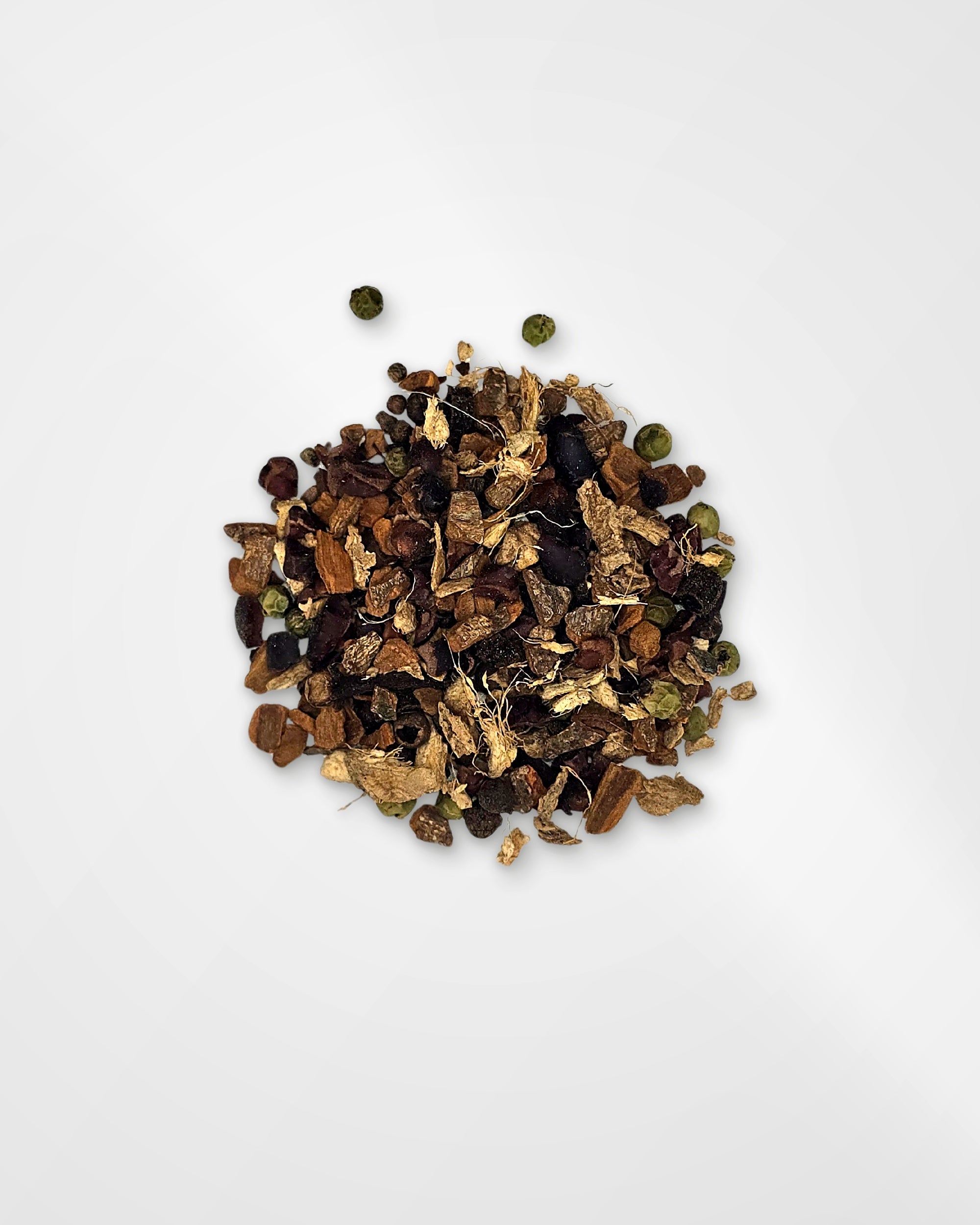 A small pile of loose dried botanical tea or spice blend with brown leaves, dark berries, and a few green round pieces, photographed on a clean white background.