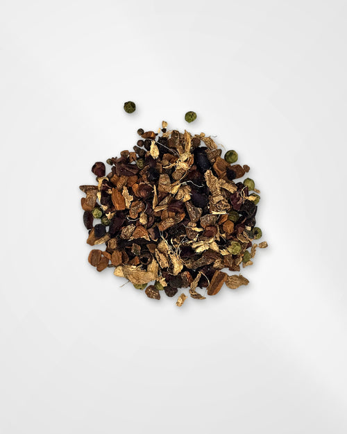 A small pile of loose dried botanical tea or spice blend with brown leaves, dark berries, and a few green round pieces, photographed on a clean white background.