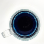 Clear glass mug with a blue tea on a white background