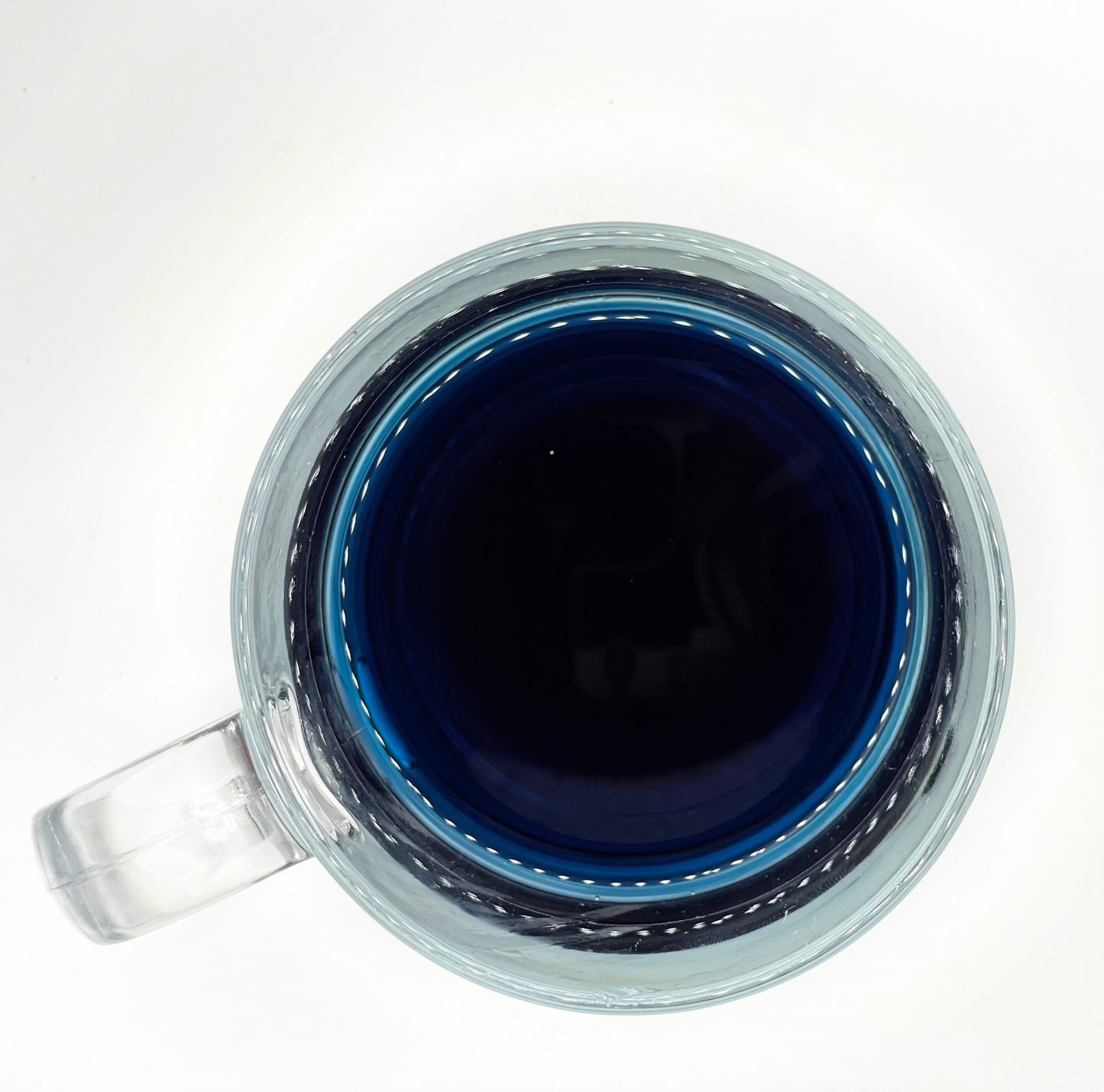 Clear glass mug with a blue tea on a white background