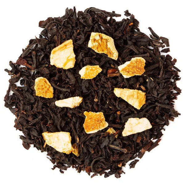 Close-up of black tea leaves with bergamot peel pieces on a white background