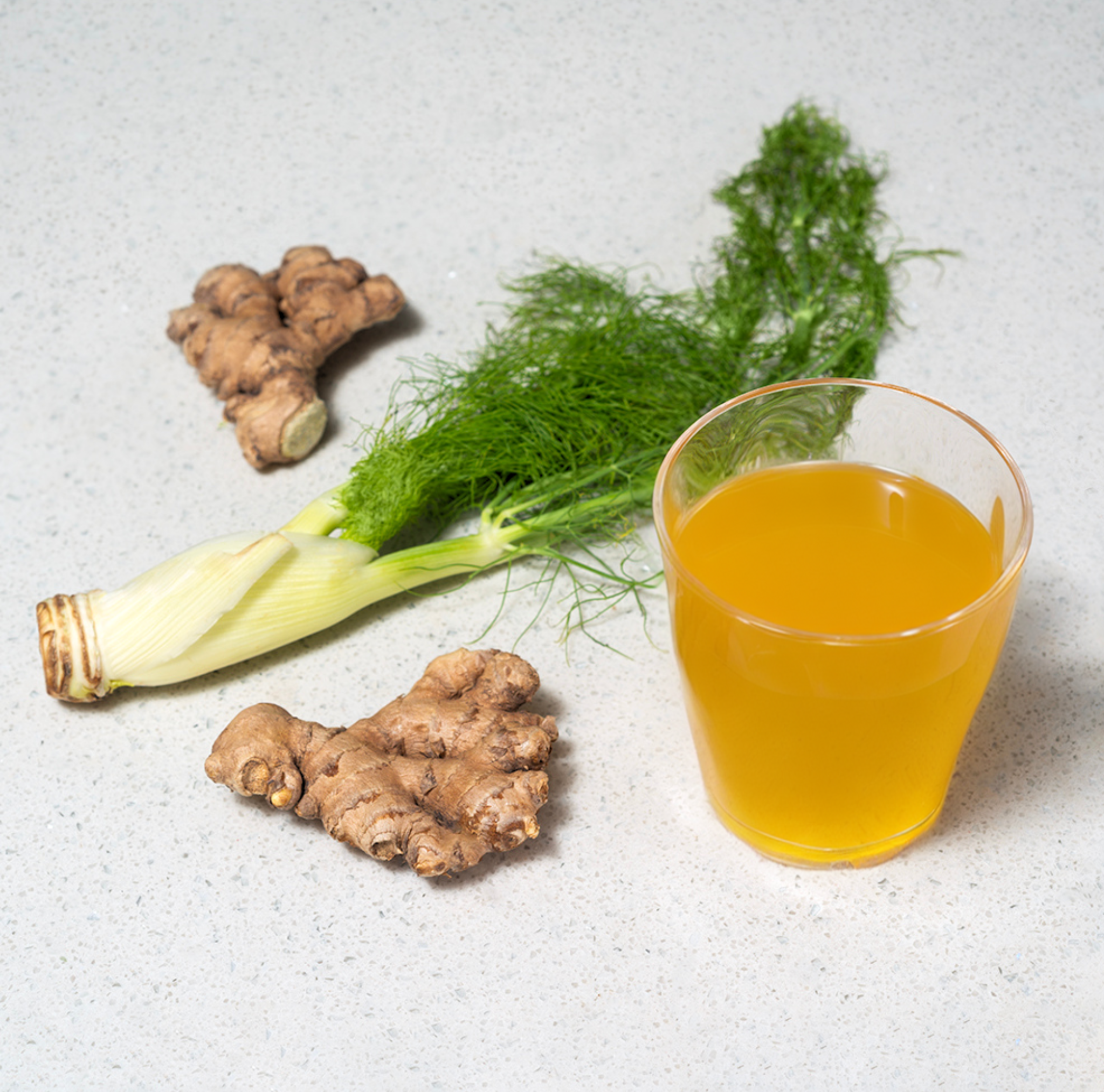 Fresh ginger and clear glass with yellow tea on a white background 