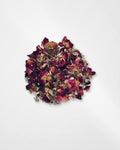 A small pile of dried rose petals and botanical pieces on a plain white background.