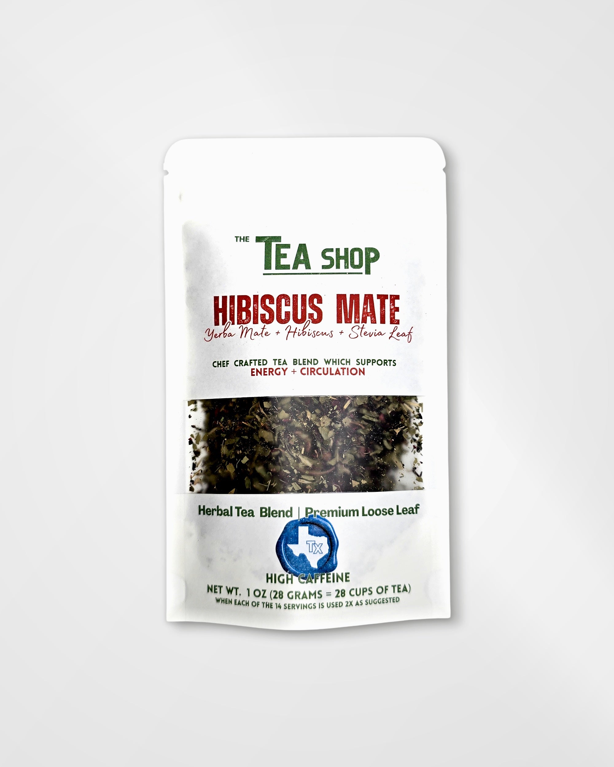 A white stand-up pouch of 'The Tea Shop' Hibiscus Mate herbal tea blend, featuring green and red text, a clear window showing the loose leaf tea inside, and a blue circular logo at the bottom, set against a light gray background.