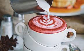 Image of a red matcha being prepared in a white stack of mugs with a blurred dining table background