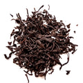 A pile of dark brown dried tea leaves on a plain white background.