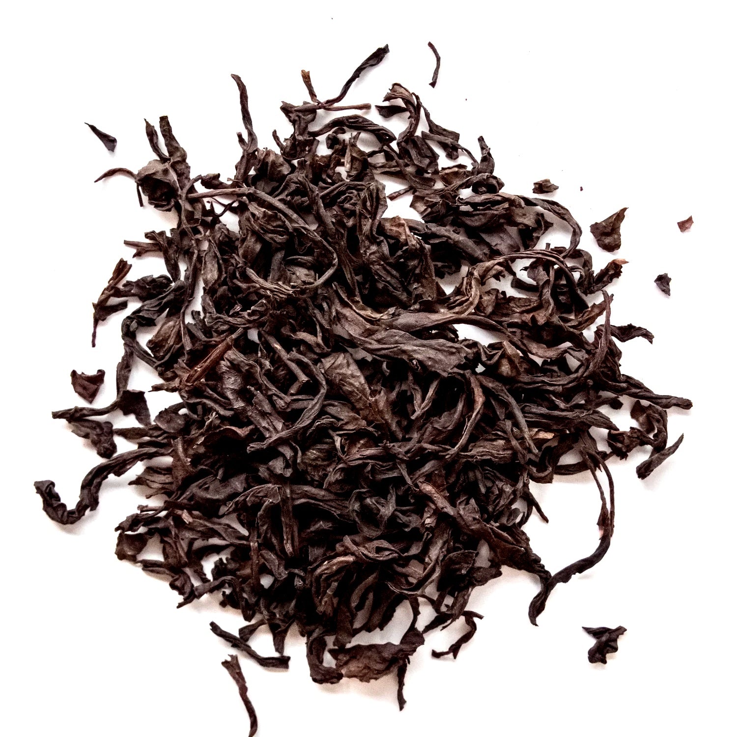 A pile of dark brown dried tea leaves on a plain white background.