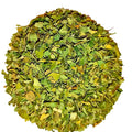 A circular pile of dried green leaves or herb pieces on a plain white background.