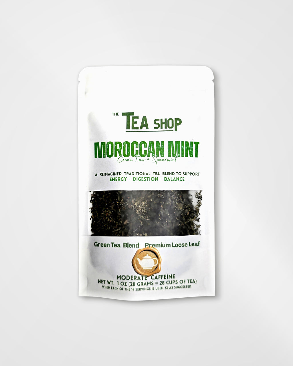 A stand-up pouch of Moroccan Mint Green Tea Blend by The Tea Shop, featuring a white package with green and black text and a clear window showing loose leaf tea inside, set against a light gray background.