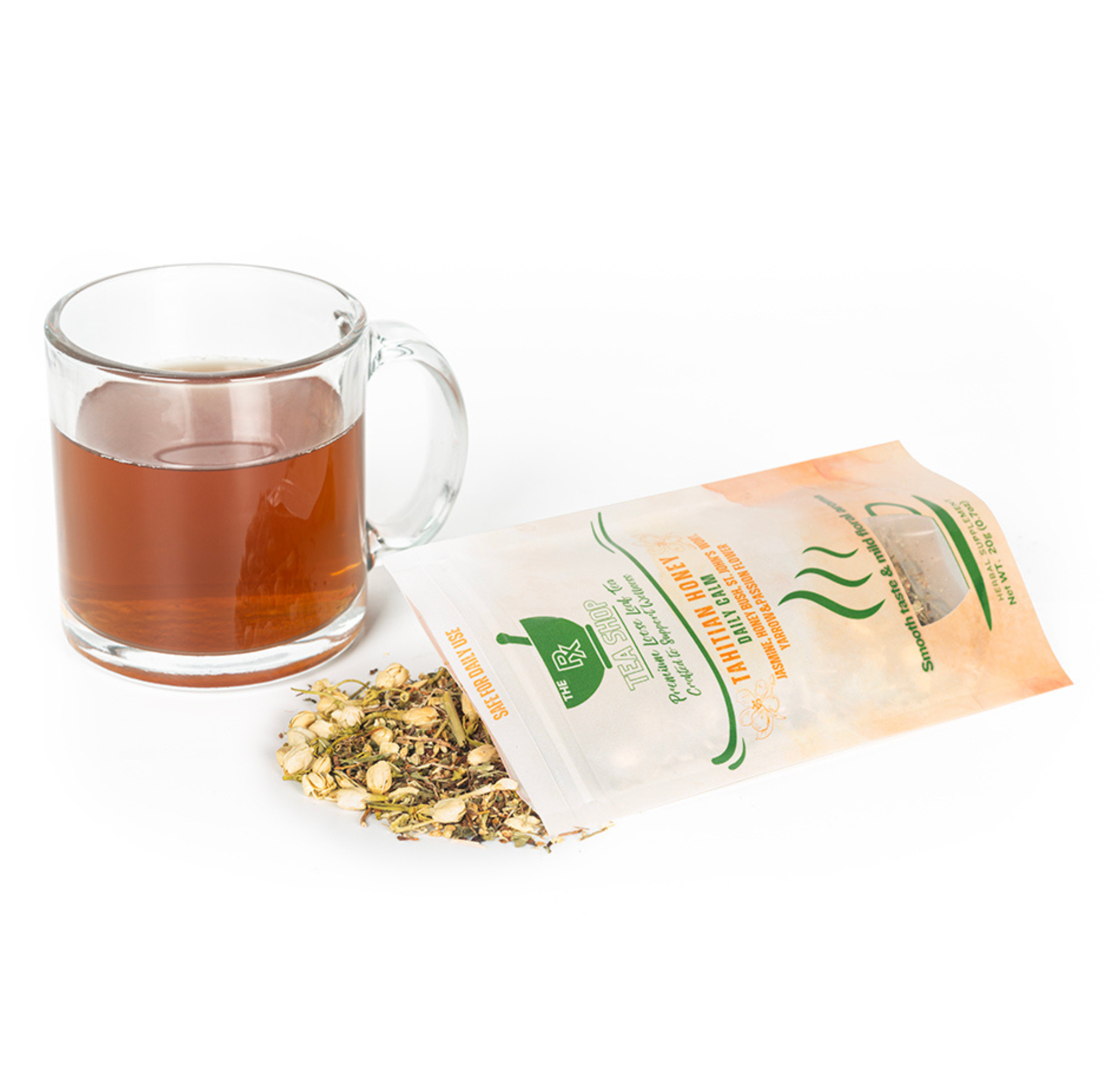 A pile of dried herbal tea leaves and petals spilling out of a bag of Tahitian Honey next to clear mug with dark colored tea on a white background