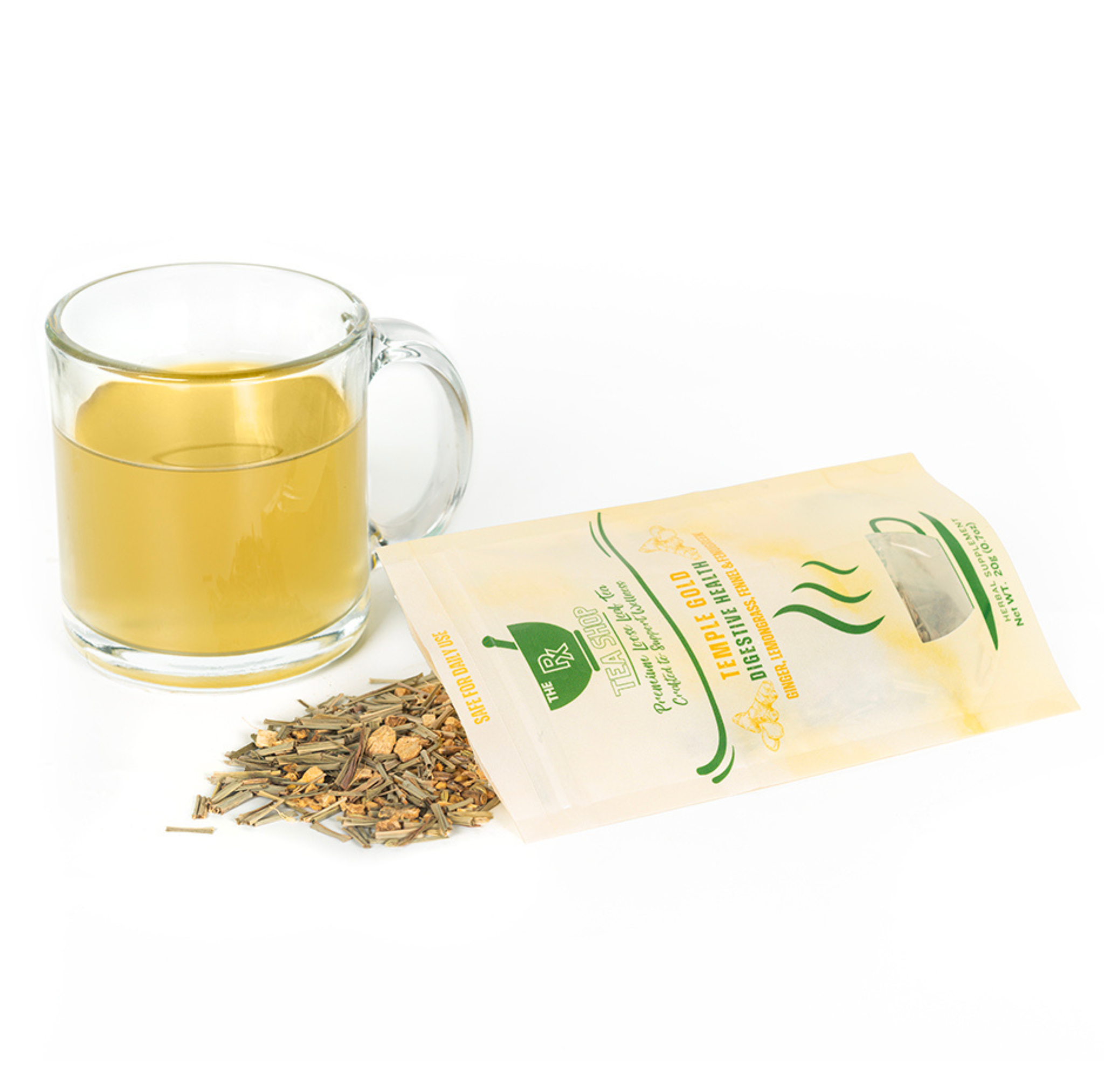 A pile of dried lemongrass and ginger pieces spilling out of a bag of Temple Gold tea next to a clear glass mug with yellow colored tea on a white background 