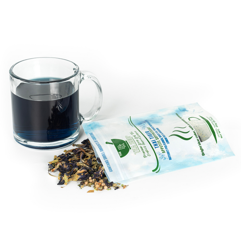 Tea bag packaging with a glass of blue tea and loose tea leaves on a white background