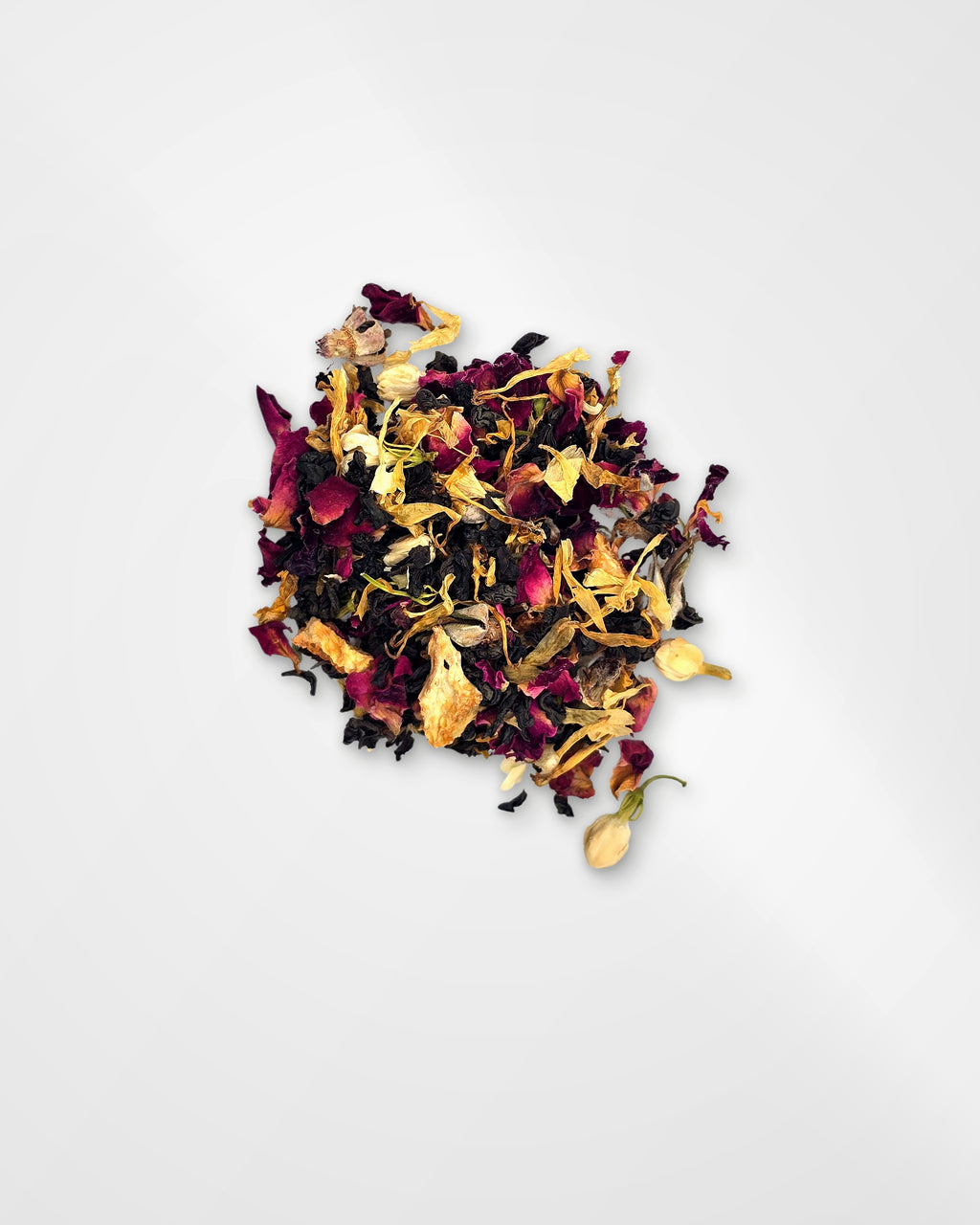 A small pile of loose-leaf herbal tea blend containing dried rose petals, yellow flower pieces, and dark tea leaves, photographed on a clean white background.