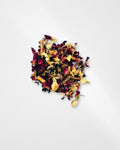 A small pile of loose-leaf herbal tea blend containing dried rose petals, yellow flower pieces, and dark tea leaves, photographed on a clean white background.