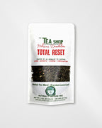 A white stand-up pouch of 'The Tea Shop' Hibiscus Dandelion Total Reset herbal tea blend, featuring a central window showing the dark loose leaf tea inside, set against a light gray background.