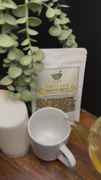 Short video clip of Temple gold tea being poured into a white teacup in a earthy toned background