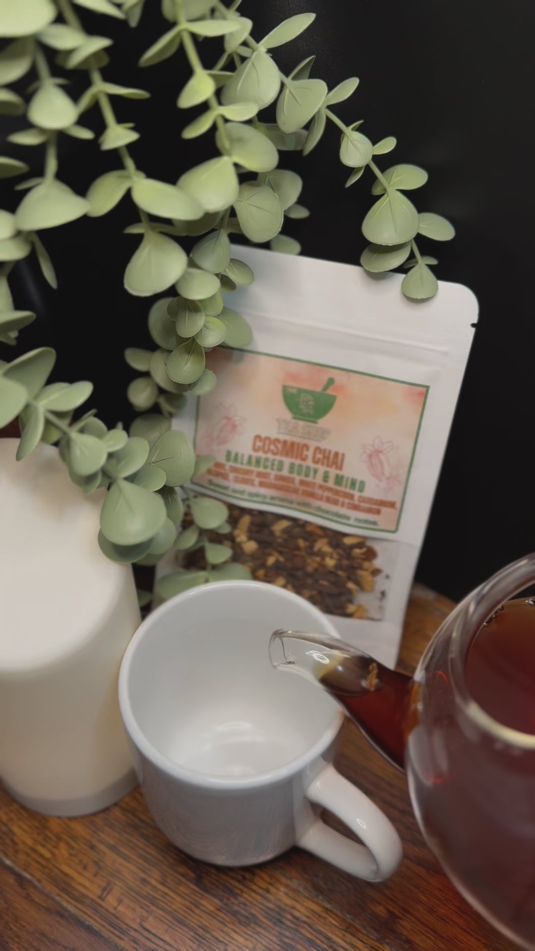 Short video clip on cosmic chai being poured into white mug from clear glass teapot with green scenery 