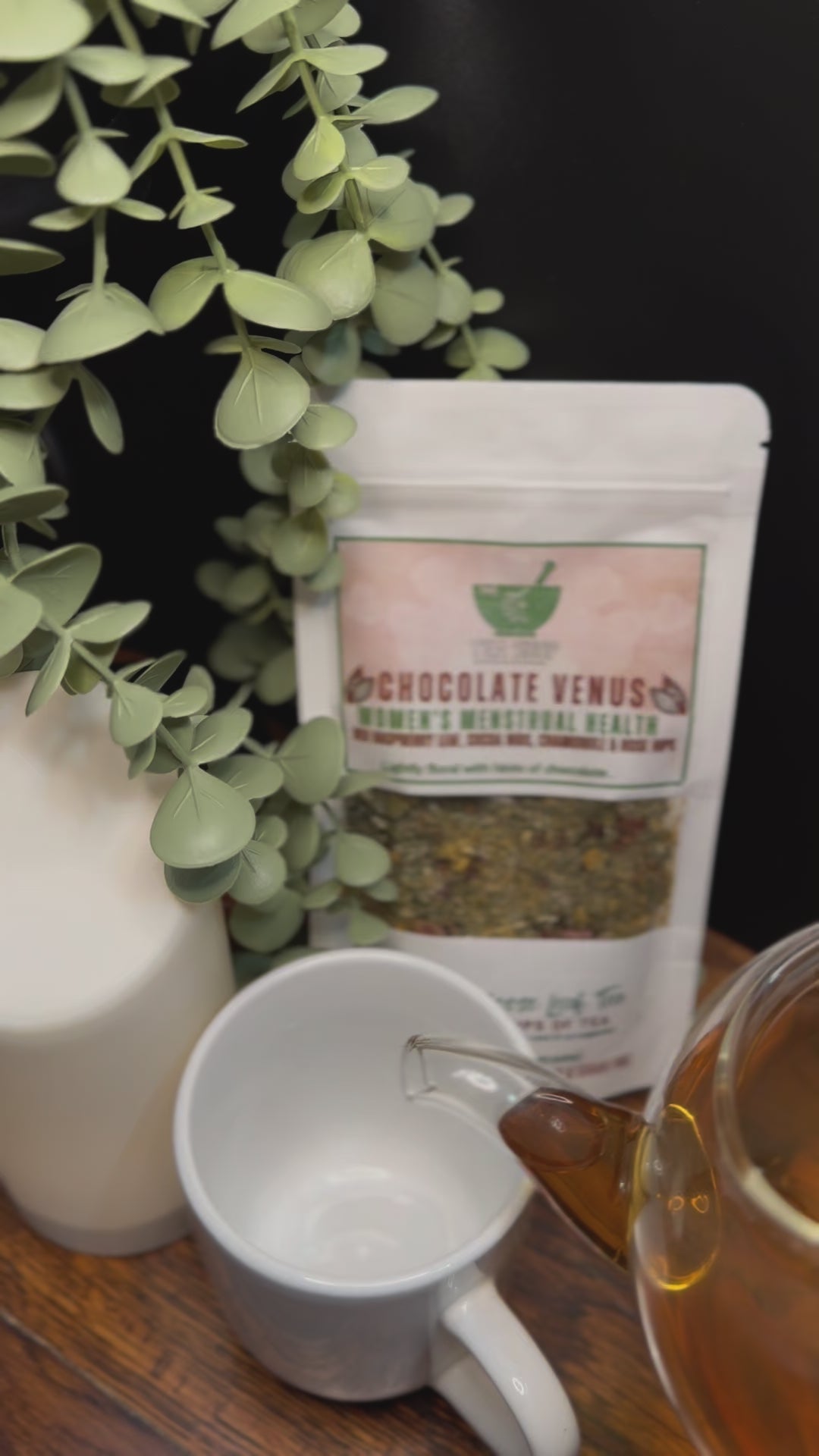 Short video clip of Chocolate venus tea being poured into white mug from clear teapot with green scenery 